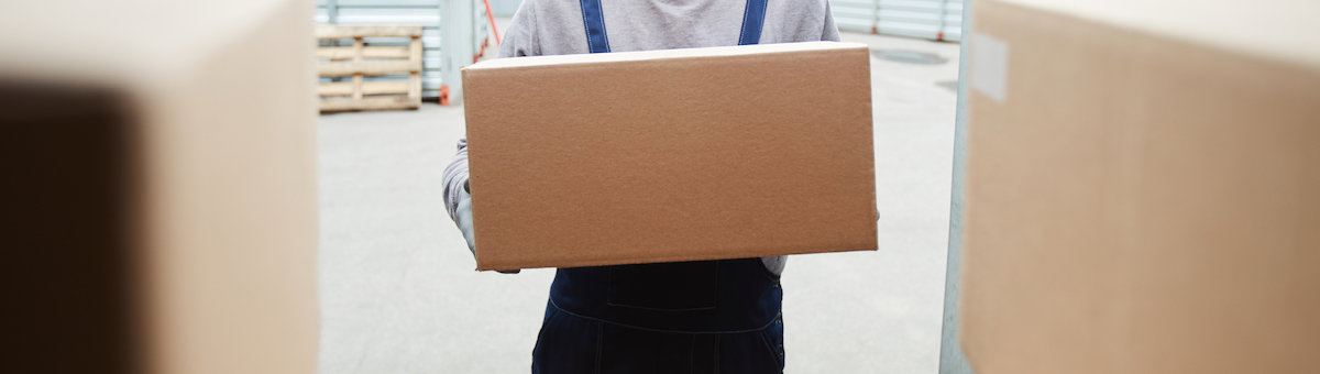 Serious handsome young manual worker putting box in container while loading goods before shipping